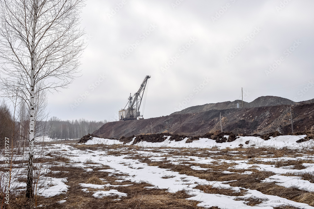 Obraz premium Piles of quartzite with a huge walking excavator and the remains of the forest in the foreground. Copy space.
