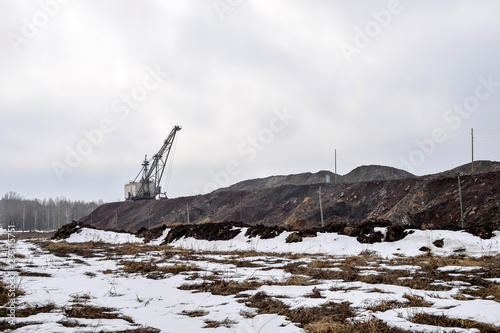 Piles of quartzite with a huge walking excavator and the remains of the forest in the background.