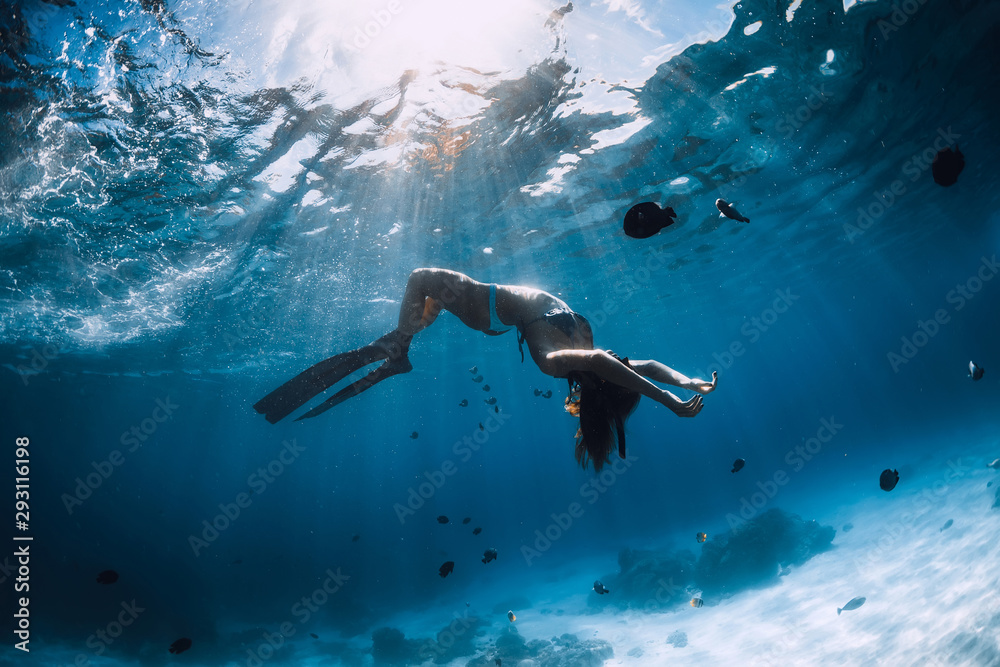 Woman freediver with fins underwater. Freediving and beautiful light in ocean