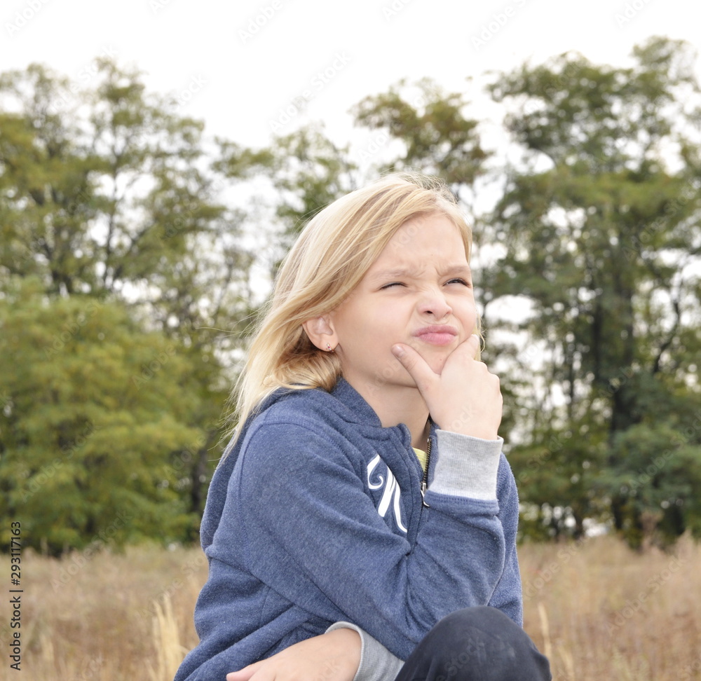 Family holiday. Portrait of a pensive, sad girl with blond hair in nature. Family holiday. Portrait of a pensive, sad girl with blond hair in nature.