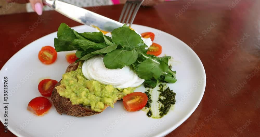 Female hands cutting avocado mashed toast an poached egg healthy breakfast. Happy tourist girl on holidays enjoying freelance work outdoors on vacation. Tropics concept. Healthy Vegan Breakfast. Female hands cutting avocado mashed toast an poached egg healthy breakfast. Happy tourist girl on holidays enjoying freelance work outdoors on vacation. Tropics concept. Healthy Vegan Breakfast.