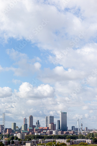 Vertical downtown cityscape of the modern city of Rotterdam with high rise buildings against a dramatic cloud filled blue sky