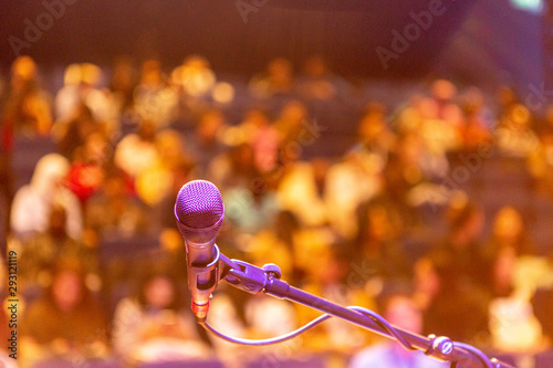 Close up of a microphone with out of focus blurred stand with people in the background