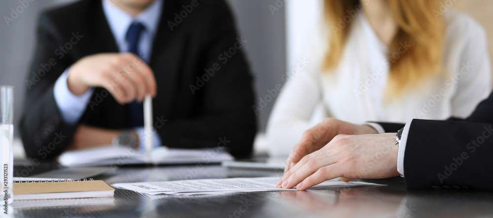 Business people or lawyers discussing questions of contract at meeting in modern office, close-up. Unknown businessman and woman with colleague sitting and working at the glass desk. Teamwork and Business people or lawyers discussing questions of contract at meeting in modern office, close-up. Unknown businessman and woman with colleague sitting and working at the glass desk. Teamwork and