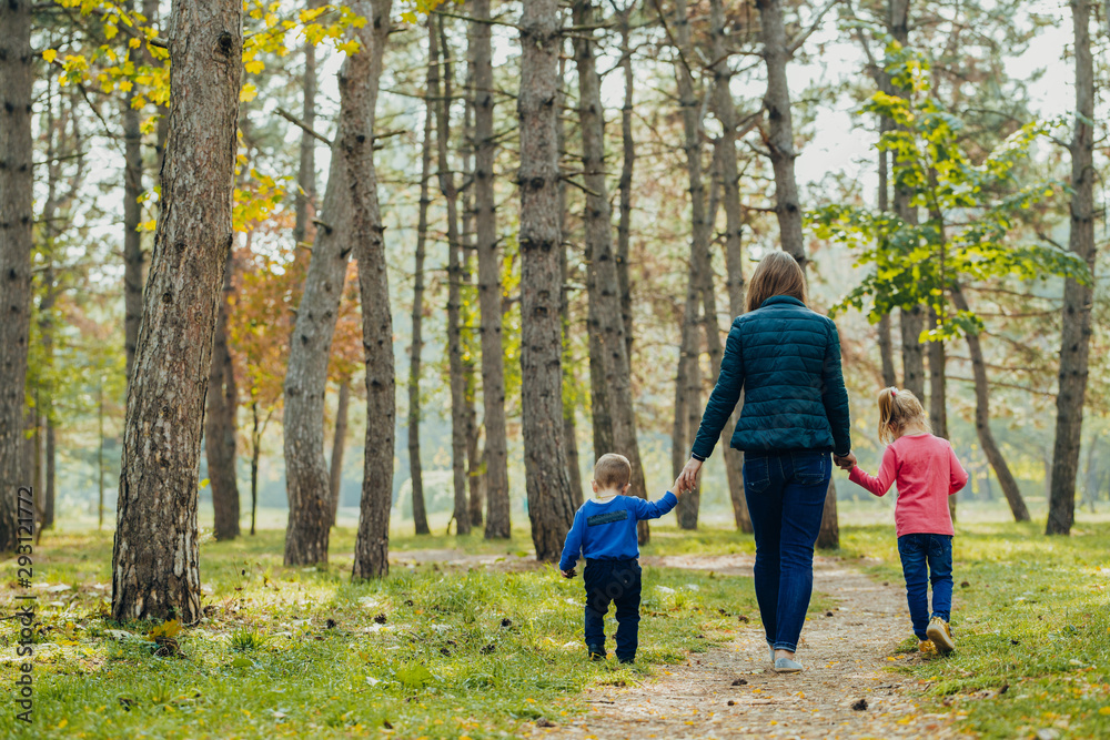 Mom with daughter and son are walking in the autumn park. Family for a walk in the forest Mom with daughter and son are walking in the autumn park. Family for a walk in the forest