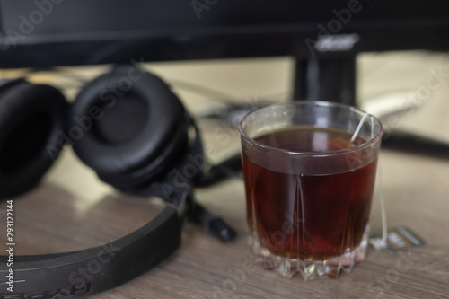 on the desktop a glass of tea, left headphones near the computer. Work lifestyle concept. office workplace