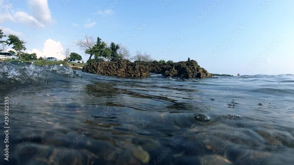 Slow motion tidal wave hitting rock shore, alternating view above water and underwater Slow motion tidal wave hitting rock shore, alternating view above water and underwater