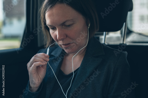 Businesswoman dictating into smartphone earphones microphone