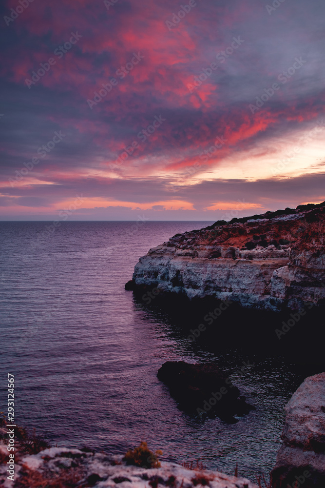 Colorful textured sky with burning clouds and ocean view of the coastline. Praia da Marinha, Famous Beach, Algarve Coast in South Portugal, Atlantic Ocean