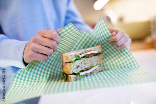 Close Up Of Woman Wrapping Sandwich In Reusable Environmentally Friendly Beeswax Wrap photo