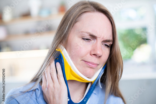 Woman Wearing Neck Brace At Home Winces With Pain