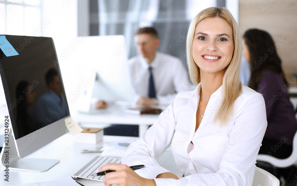 Business woman using computer at workplace in modern office. Secretary or female lawyer smiling and looks happy. Working for pleasure and success Business woman using computer at workplace in modern office. Secretary or female lawyer smiling and looks happy. Working for pleasure and success