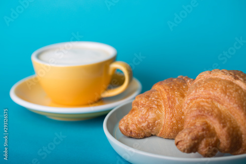 yellow cup with croissant on a blue background