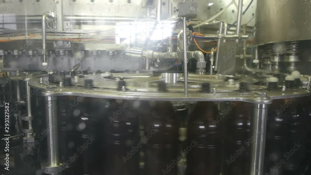 Beer is pouring into rotating plastic bottles from a factory machine Beer is pouring into rotating plastic bottles from a factory machine