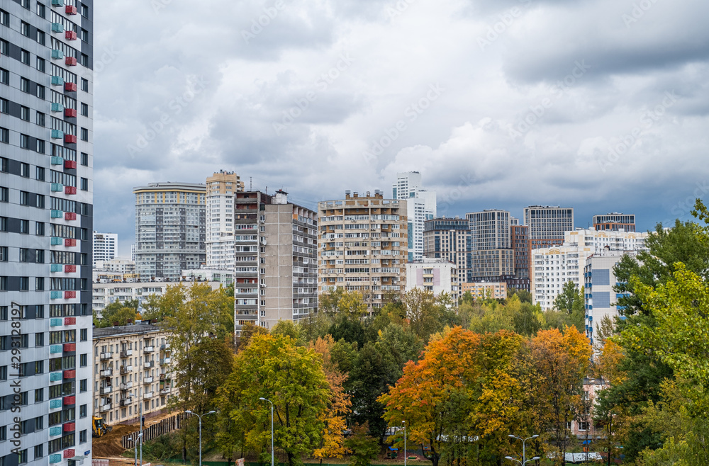 Obraz premium View to the residential buildings from the hill, overgrown with grass and wild flowers of goldenrod. Concept of ecology in a city, suburb area, eco-friendly district