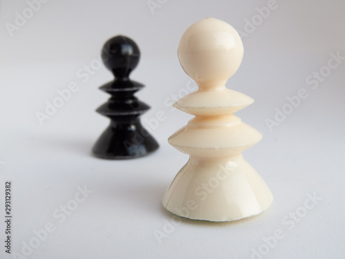 One white chess piece standing in front and one black chess piece standing in the back  focus on white one in front