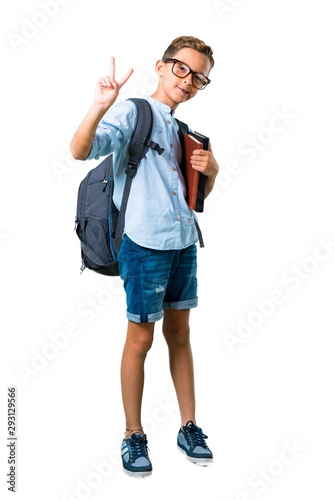 Full body of Student boy with backpack and glasses smiling and showing victory sign on isolated white background © luismolinero