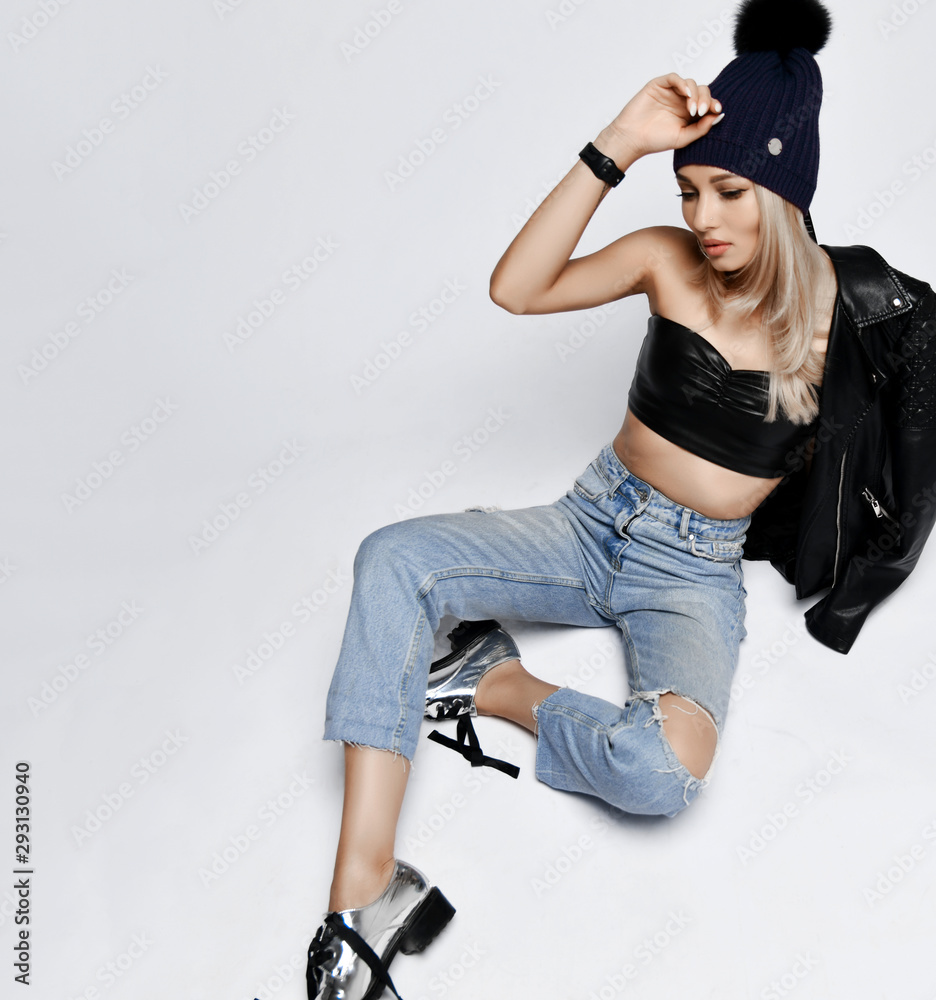 Grunge style woman in torn jeans, leather top and jacket, sitting on floor  touching her purple winter hat with pompon Stock Photo | Adobe Stock