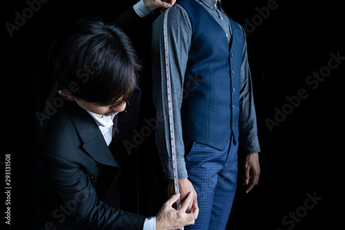 The dressmaker was using a tape measure to measure the length of the arm on a black background.