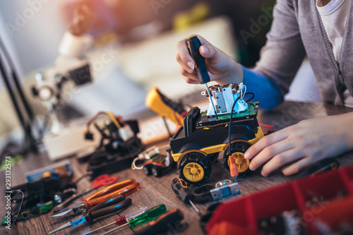 Girl constructs technical toy. Technical toy on table full of details