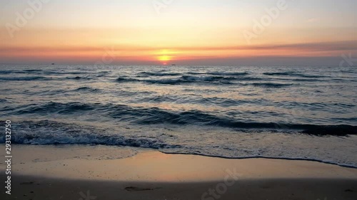 Red-orange sunset on the sea with a prominent sailing yacht on the horizon. Bright colors of sea sunset.