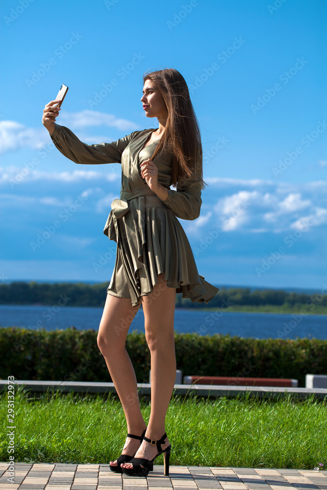 Young beautiful woman in green dress walking on the summer street