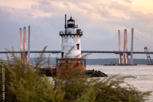 Caisson (sparkplug) style lighthouse under soft golden light with a bridge in the background. Tarrytown Light on the Hudson River in New York. 