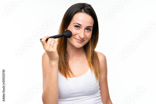 Young woman holding a lot of makeup brush over isolated white background