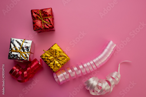 Gift Boxes Silver, Golden, Red and Decorative Ribbons Lie on a Pink Background.