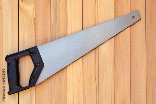 Hacksaw hand on wood with a black handle close-up. hand saw for sawing trees on a wooden background. Hand tools for carpentry.