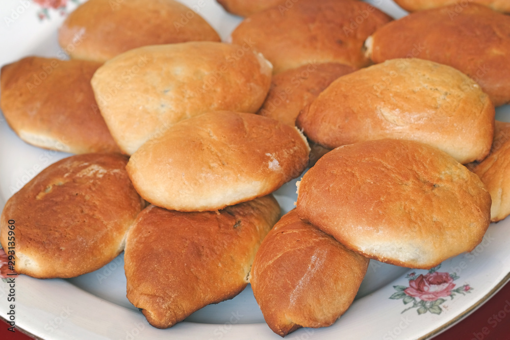 Baked pasties stuffed on a dish. Homemade buns with apples. Butter, sweet pastries for tea.