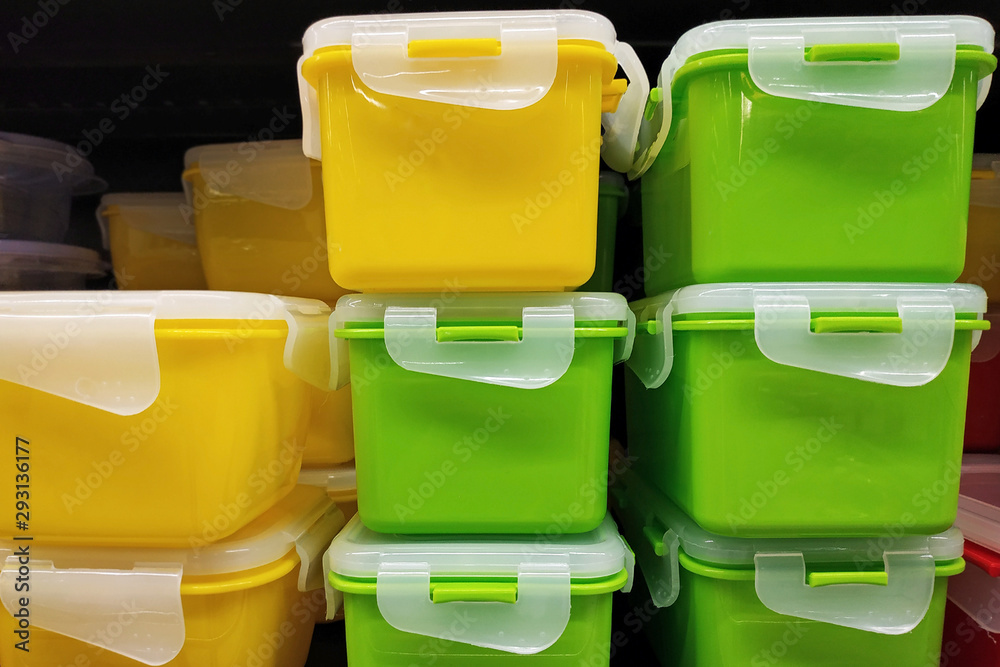 Fototapeta premium Green and yellow plastic containers with a lid, close up. Universal food containers. Bright plastic boxes with lids for storing food and vegetables. Modern kitchen utensils in the store.