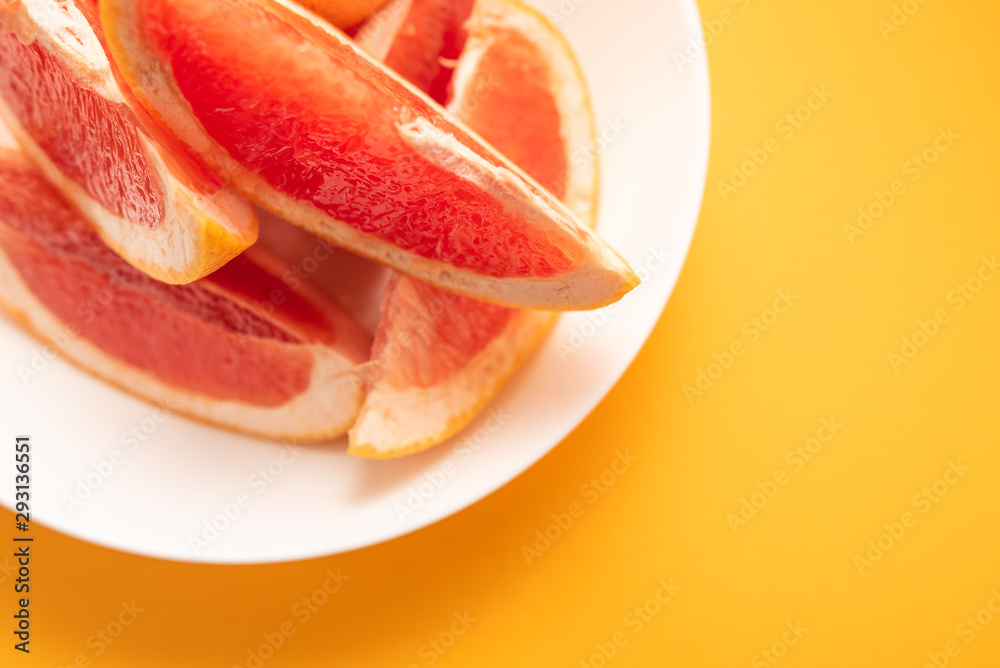 Fresh ripe juicy grapefruit on white plate on yellow background. Fresh ripe juicy grapefruit on white plate on yellow background.
