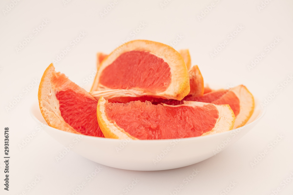 Fresh ripe juicy grapefruit on white plate on white background.