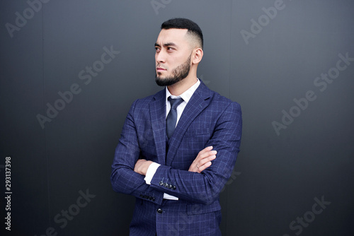 Asian Kazakh businessman with a serious facial expression on a black wall background