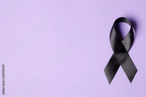 Black ribbon on a lilac background. Mourning. Sorrow.