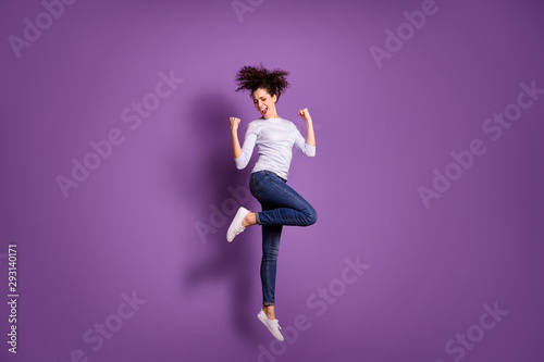 Full length body size photo of cute nice strong beautiful woman wearing jeans denim jumping up with victorious isolated over pastel purple color background