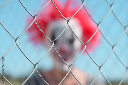 scary clown behind a fence
