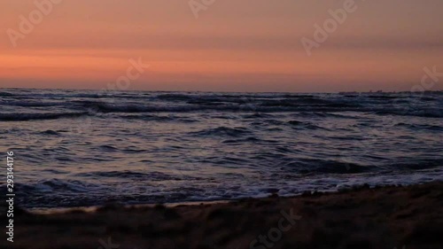 Red-orange sunset on the sea with a prominent sailing yacht on the horizon and flying birds.  Bright and dark colors of the sea sunset.
