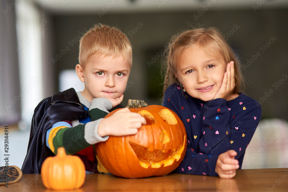 Fototapeta premium Portrait of charming little boy and girl with halloween pumpkin