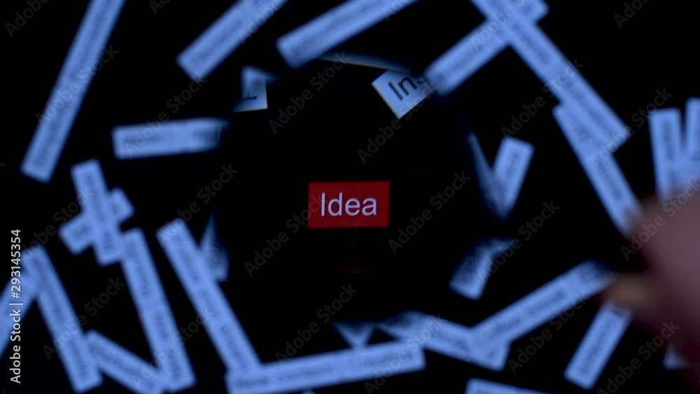 Hand with magnifier focuses on phrase Idea. Finding solutions. Tag cloud on  dark wooden table.