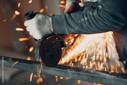 Fotografie Craftsman sawing metal with disk grinder saw in workshop