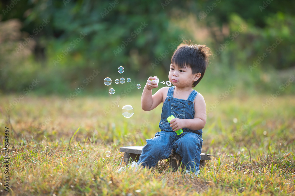 Little boy blowing soap bubbles outdoor at sunset - happy carefree childhood Little boy blowing soap bubbles outdoor at sunset - happy carefree childhood