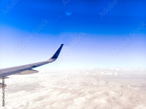Wing of the plane on blue sky background .  Airplane Wing in Flight from window  blue sky . travel concept idea .