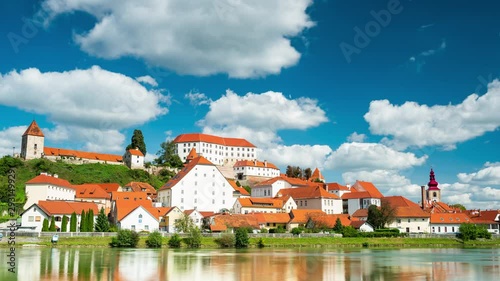 Picturesque City of Ptuj at River Drava in Slovenia. 4K Time Lapse on Beautiful Day with Moving Clouds and Water Reflection.