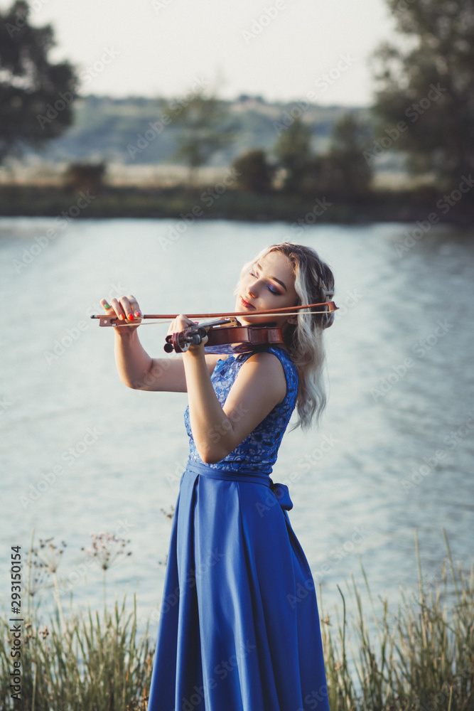 romantic young woman with a violin at dawn on river bank, elegant girl ...