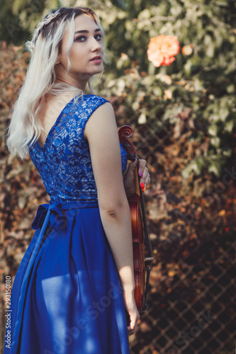 portrait of a beautiful young woman with a violin in garsen with flowers, girl walking on nature, concept music and hobbies photo