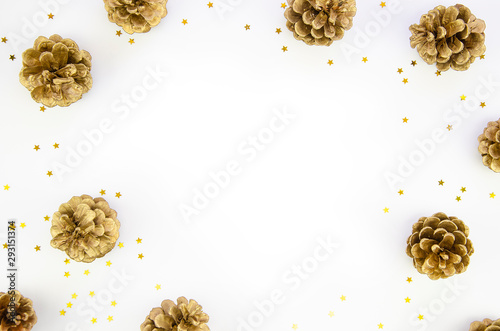 Christmas frame with golden star confetti and pine cones on white background. Flat lay with copy space. New Year 2020 concept