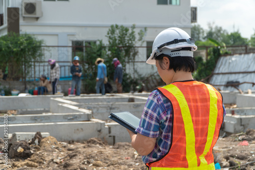 Portrait of Asian woman construction engineer worker with helmet on head using tablet while standing on construction site. building site place on background. Construction concept