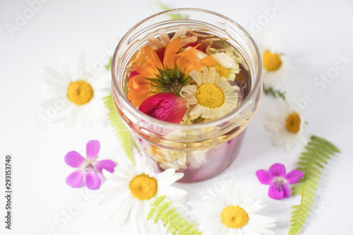 glass bottle oil based on various medicinal herbs and flowers  cosmetic oil for skin care on white background